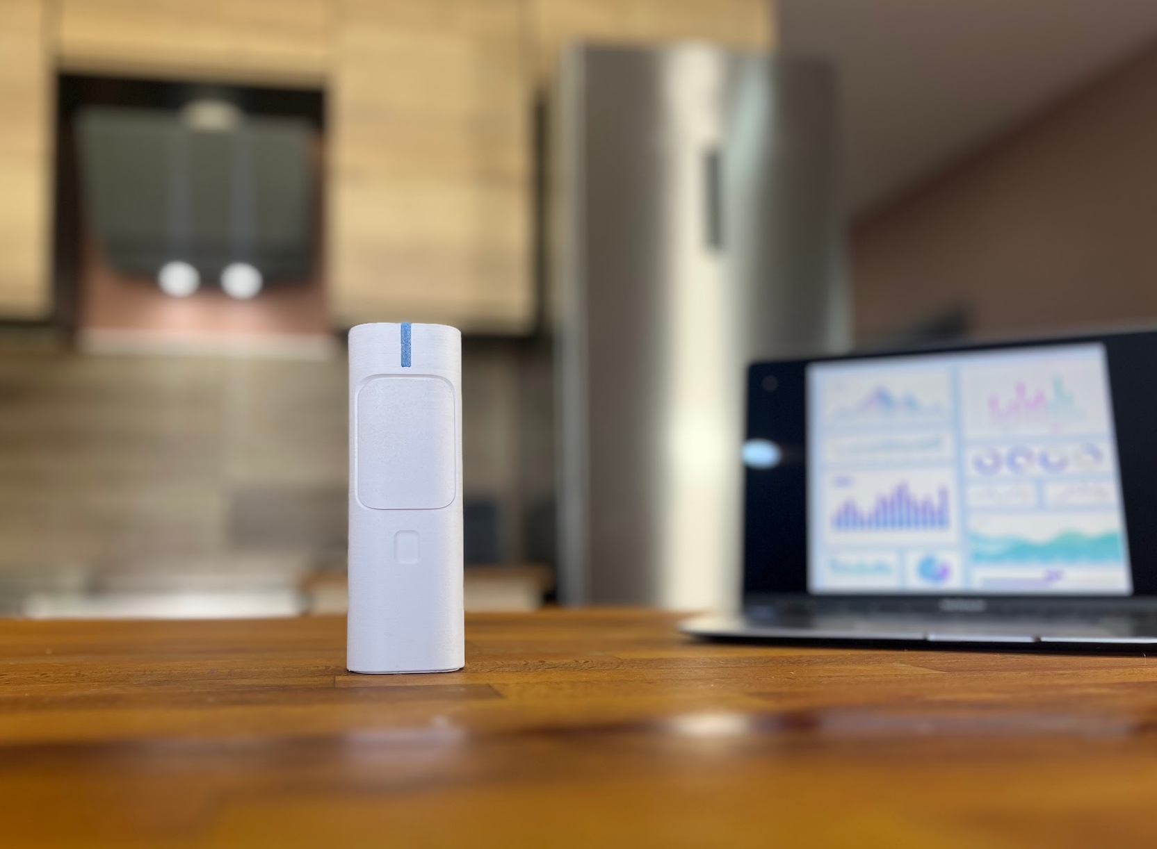 FrigoSense device on a countertop next to a laptop showing the web dashboard